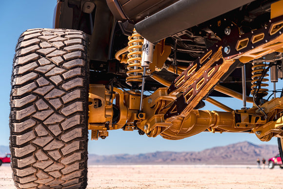 Close-up of a vehicle's suspension system with a desert landscape in the background