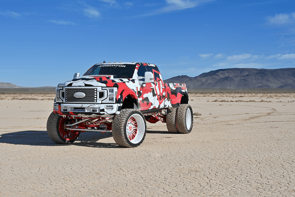 Ford F450 Camouflage-patterned truck in a desert landscape with mountains in the background With Premium Predator New Mutant X-MT on it
